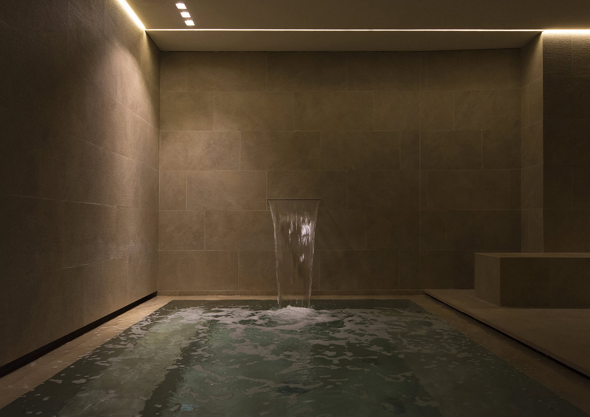 Borgo Cadonega Spa, ambiente piscina totalmente rivestita in ceramica effetto pietra e cascata
