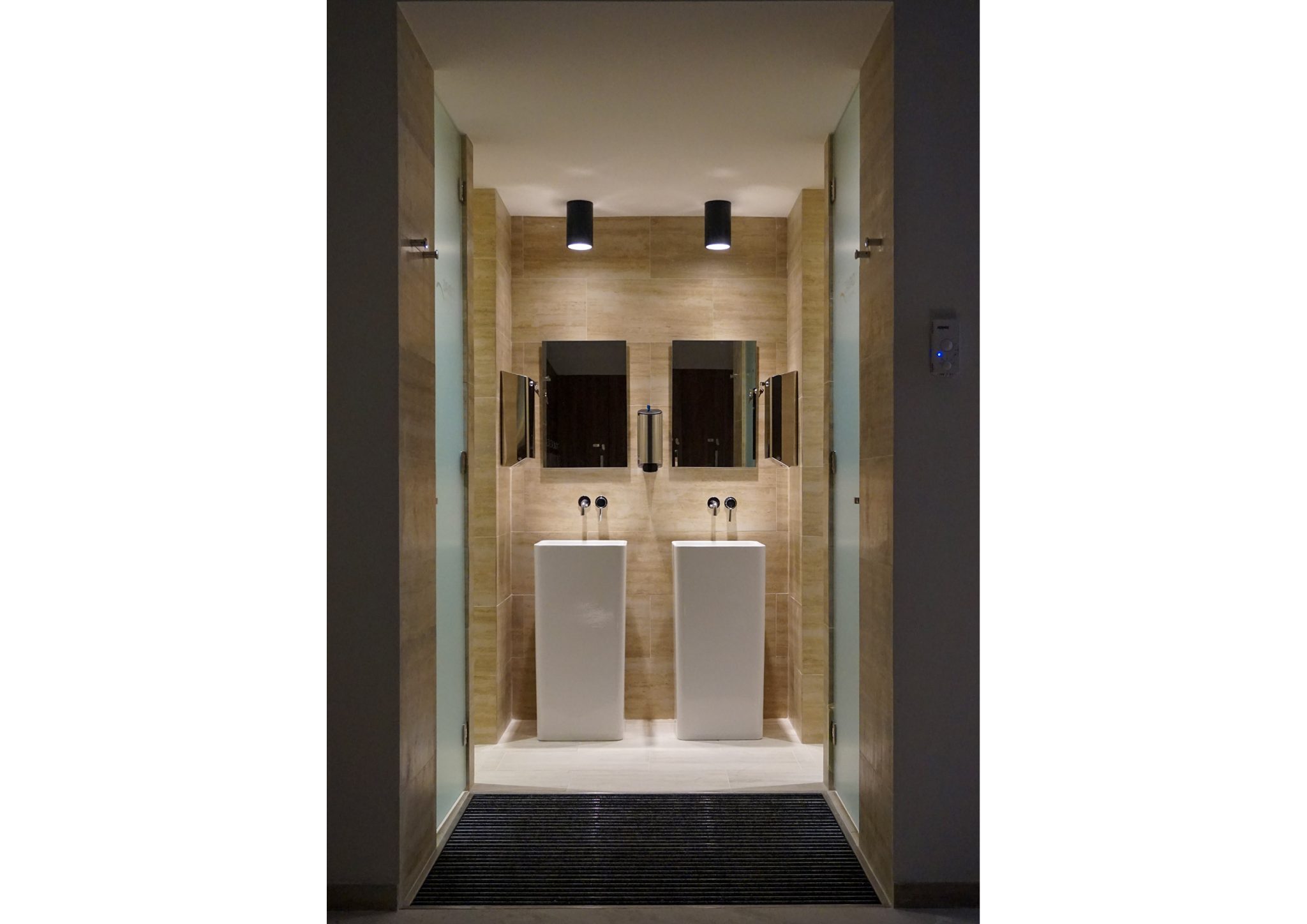 American Express Fitness Club, vista frontale spogliatoi con rivestimenti a parete in pietra e doppio lavabo